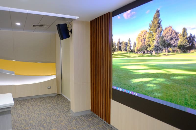 High-resolution digital display screen showing lush green golf course scenery in a modern conference room.