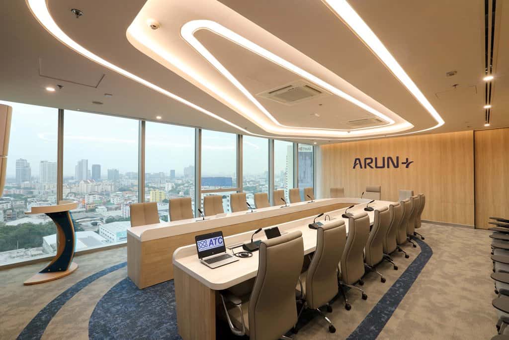 Modern meeting room with large windows, high-tech equipment, and corporate branding for บริษัท แอ็ดว้านซ์ เทคโนโลยี คอนแทรคติ้ง จำกัด, ideal for business and technology projects.